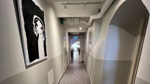 A hallway with a tiled floor, white walls, and a black and white artwork on the left. - Hostel Dalagatan (Stockholm)