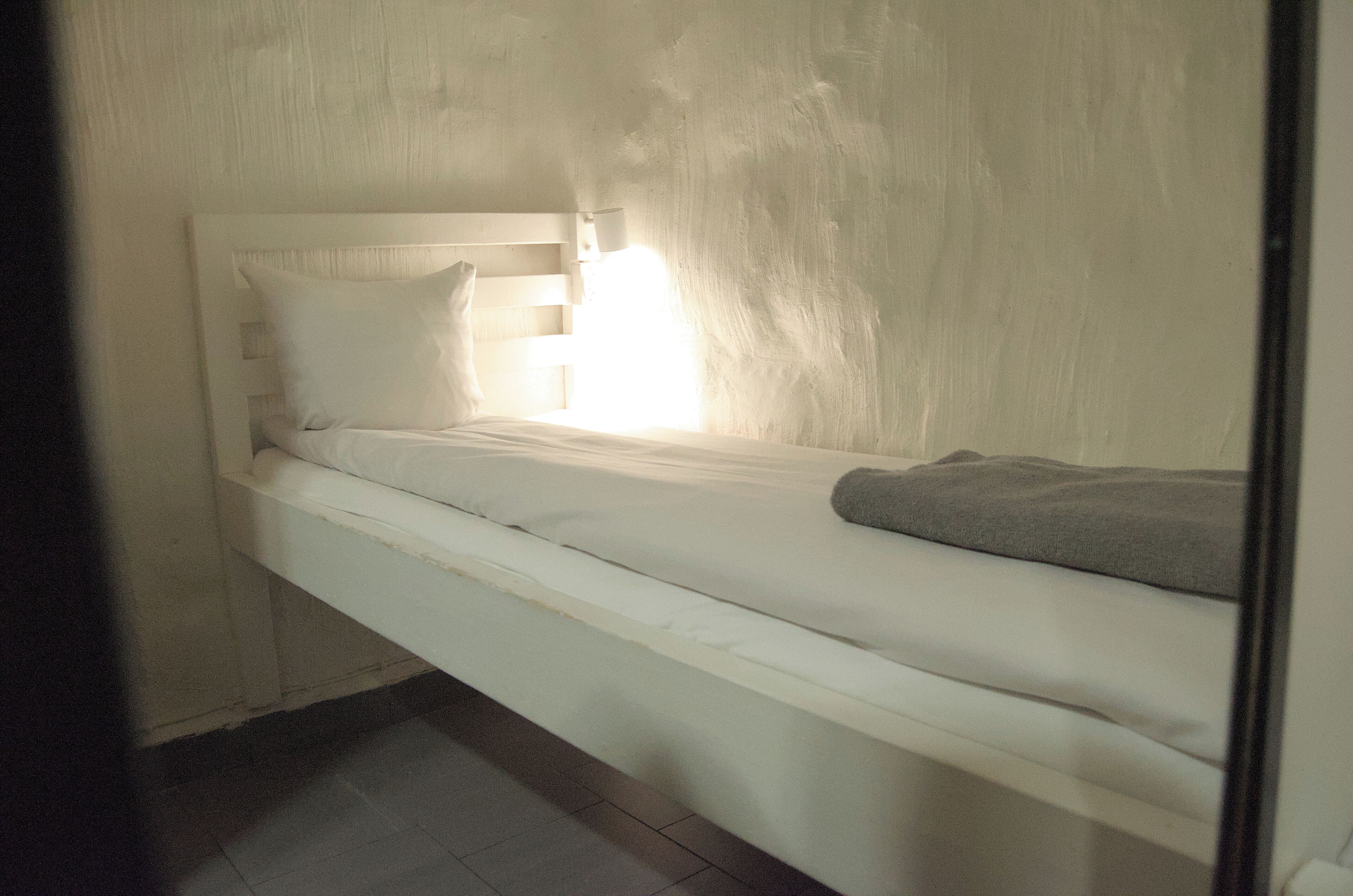 A single bed with a headboard, a pillow, and a blanket.