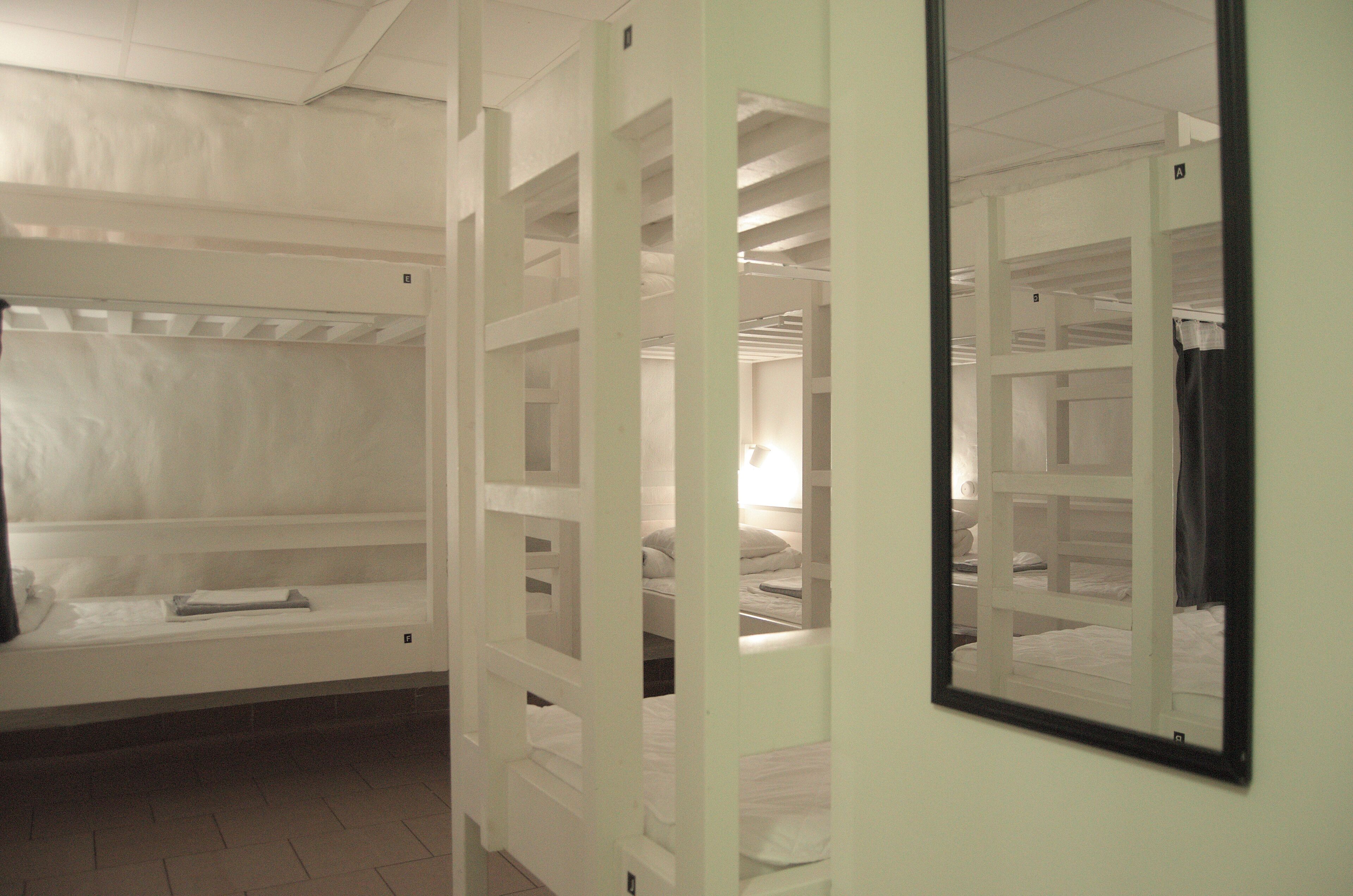 Een kamer met stapelbedden, een spiegel en een bank.