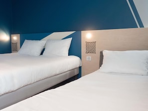 Ein Hotelzimmer mit zwei Betten, einem Holzkopfende und Wandleuchten.