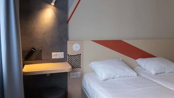 Una habitación de hotel moderna con cama, mesita de noche y lámpara de pared.