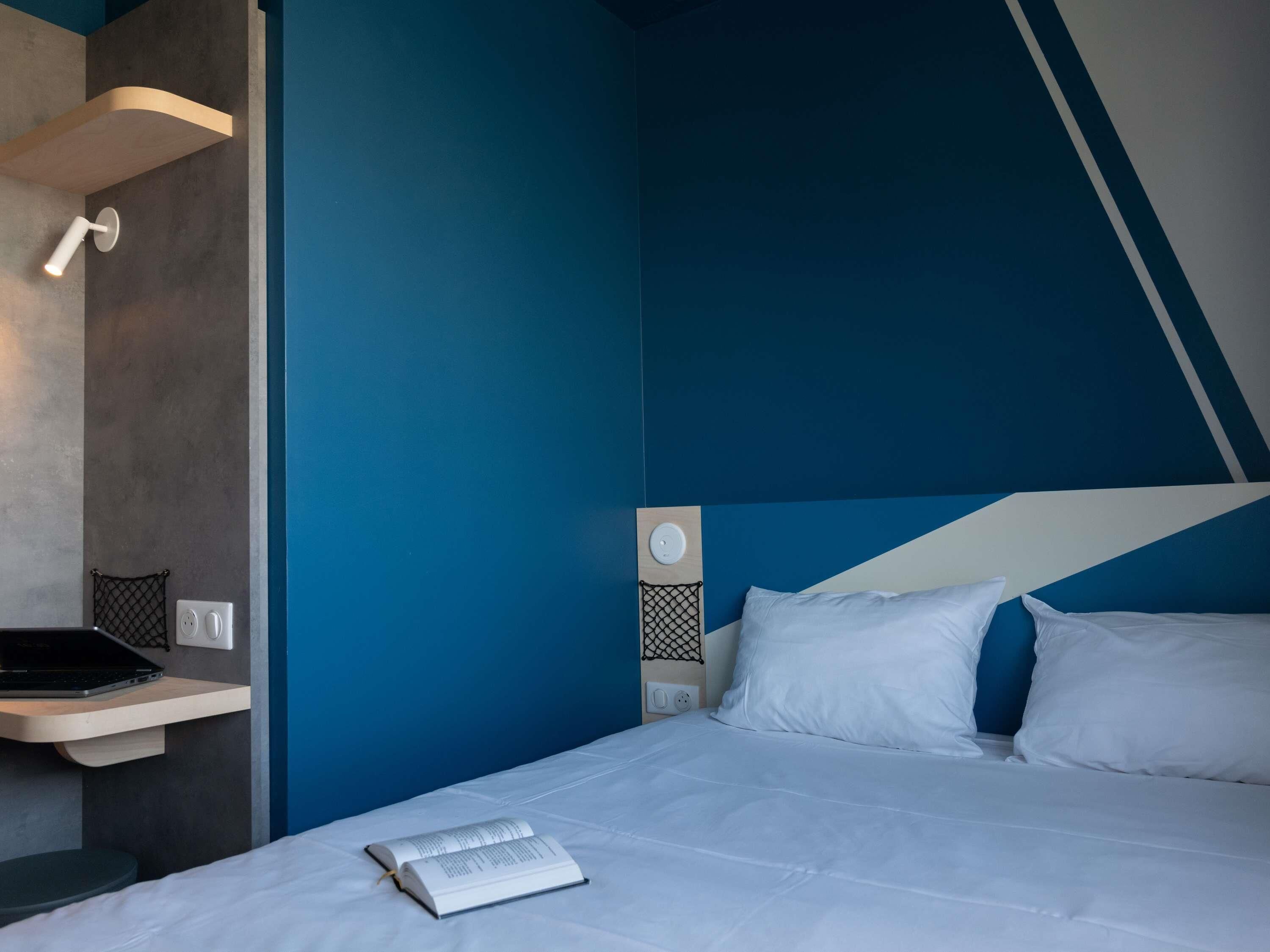Une chambre d’hôtel moderne équipée d’un lit, d’un bureau et d’un ordinateur portable.
