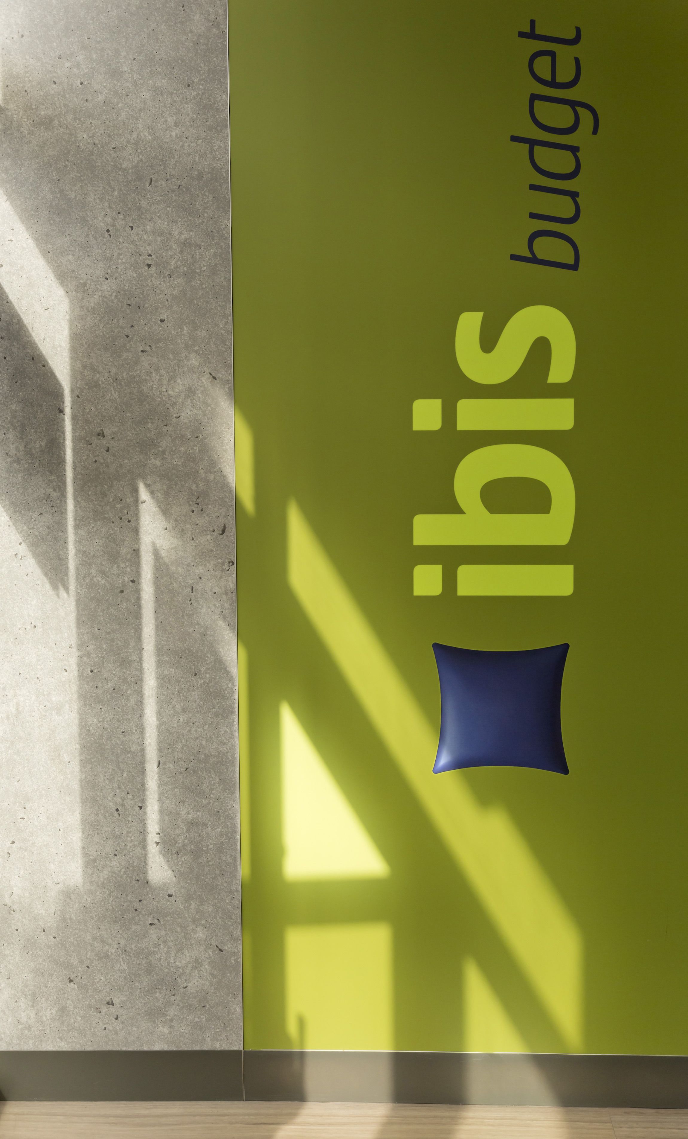 A wall with the text "ibis budget" and a blue pillow.