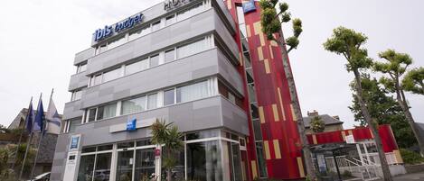 Ein Hotel mit modernem Design, erkennbar am gut sichtbaren Schriftzug 'Hotel' und dem 'Ibis'-Logo.