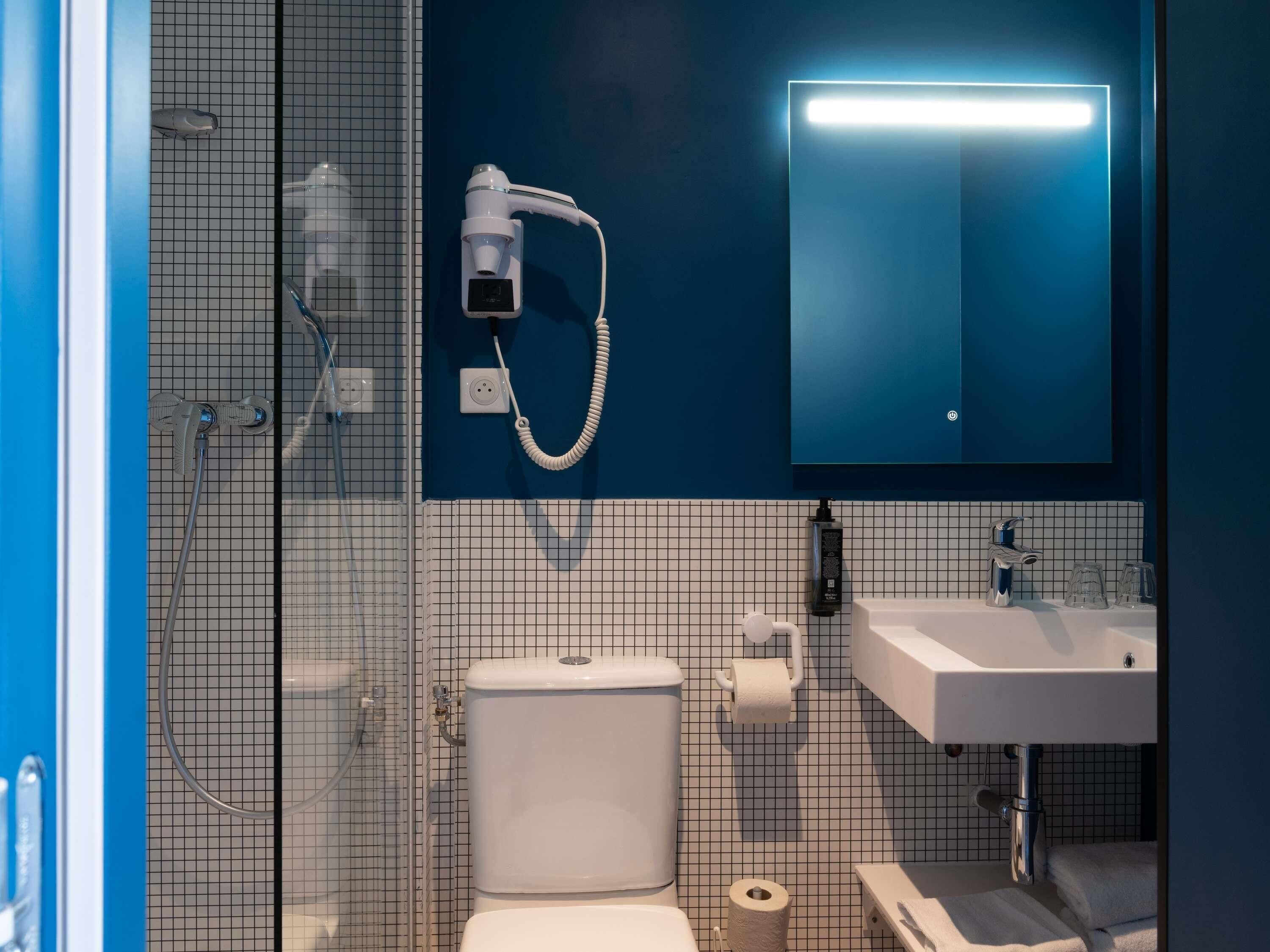 Un baño con ducha, inodoro, lavabo y espejo con luz.
