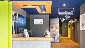 A reception desk with a wooden counter, a framed picture on the wall, and a poster with a snowflake design.