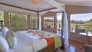 A spacious bedroom with a large bed, a wooden floor, and a view of the outdoors. - Loyk Mara Camp (Maasai Mara)