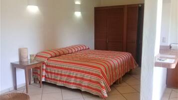 Un dormitorio con cama, mesita de noche, armario de madera y zona de baño.