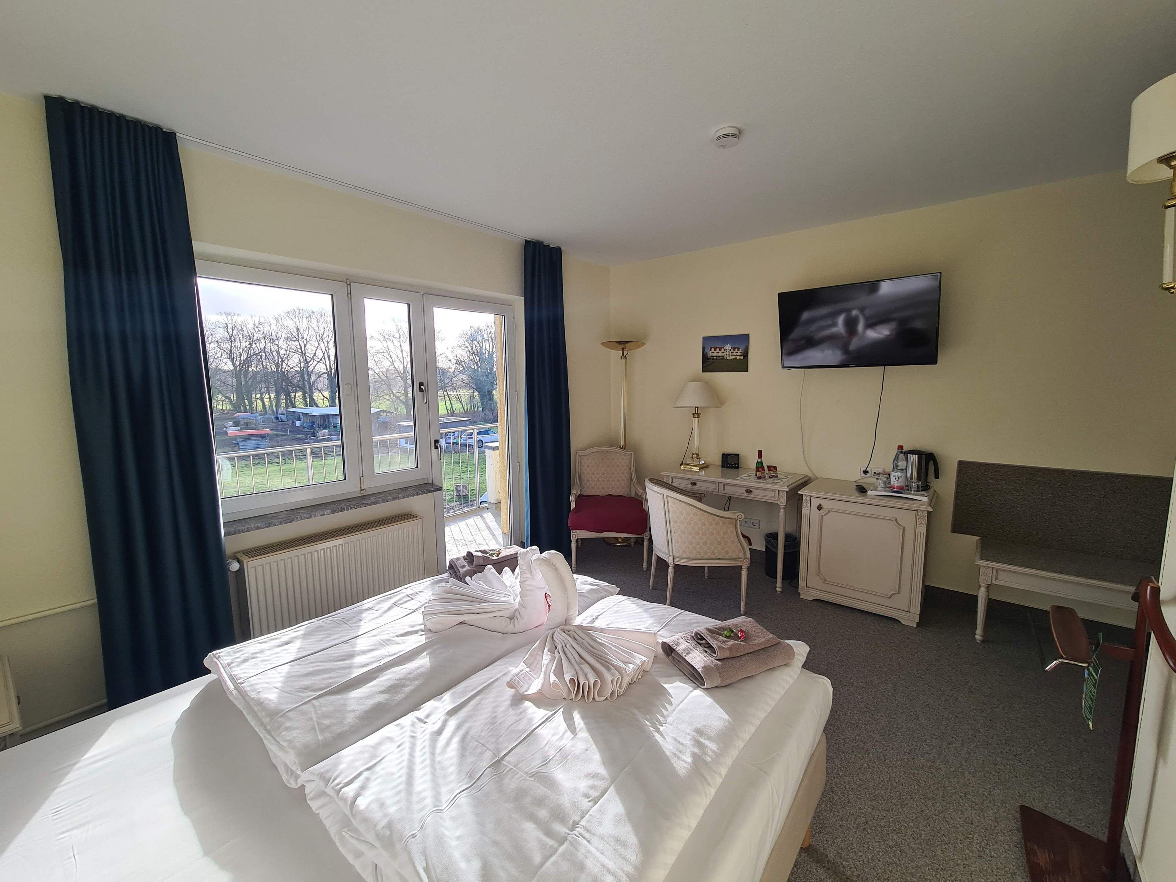 Habitación de hotel con cama, escritorio, silla, televisor y vista al exterior.