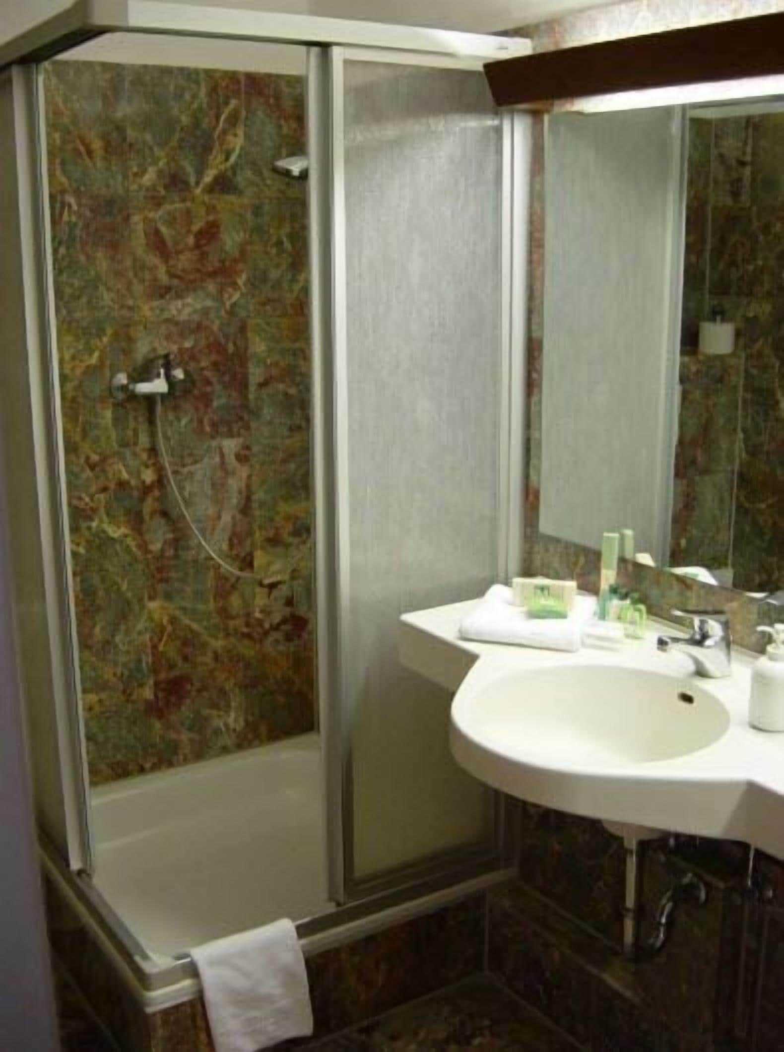 A bathroom with a shower, a sink, and a mirror.