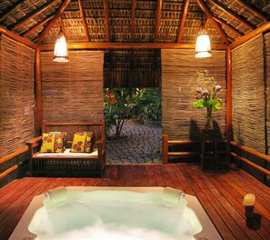 A wooden spa room with a hot tub, wicker furniture, and a stone pathway leading outside. - Pousada Calypso (Porto Seguro)
