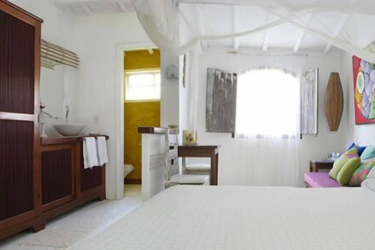 A bedroom with a large bed, wooden headboard, a bedside table, a chair, and a wardrobe.