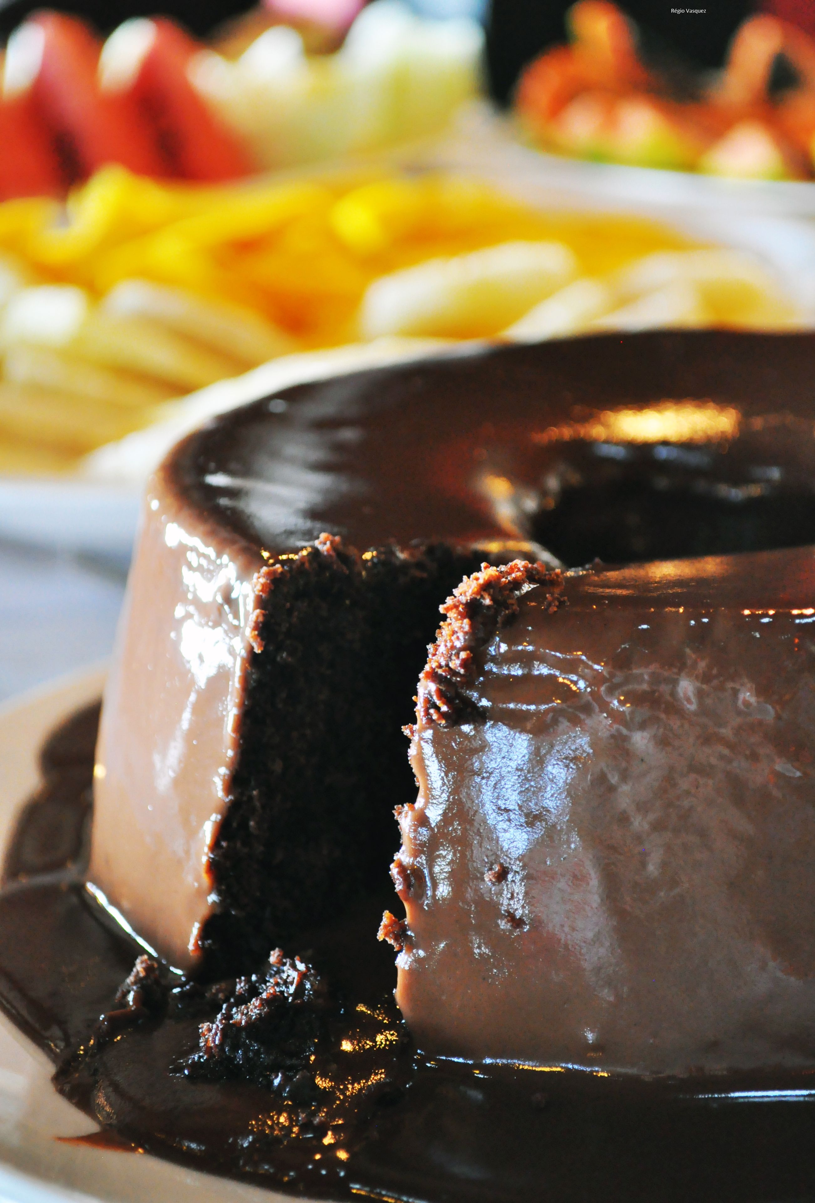 Um bolo de chocolate com cobertura brilhante e uma fatia retirada.