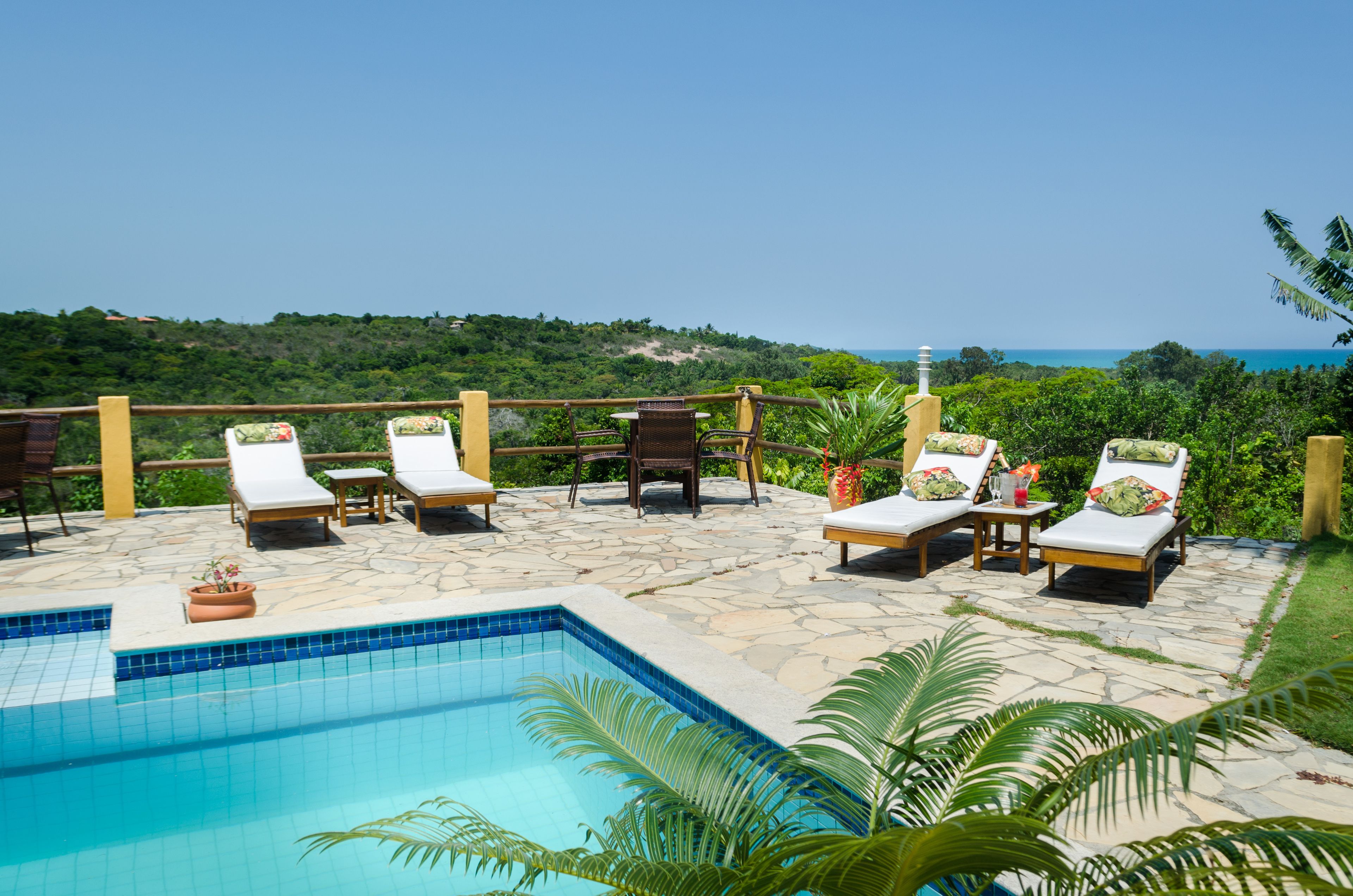 A poolside area with lounge chairs and a view of the ocean.