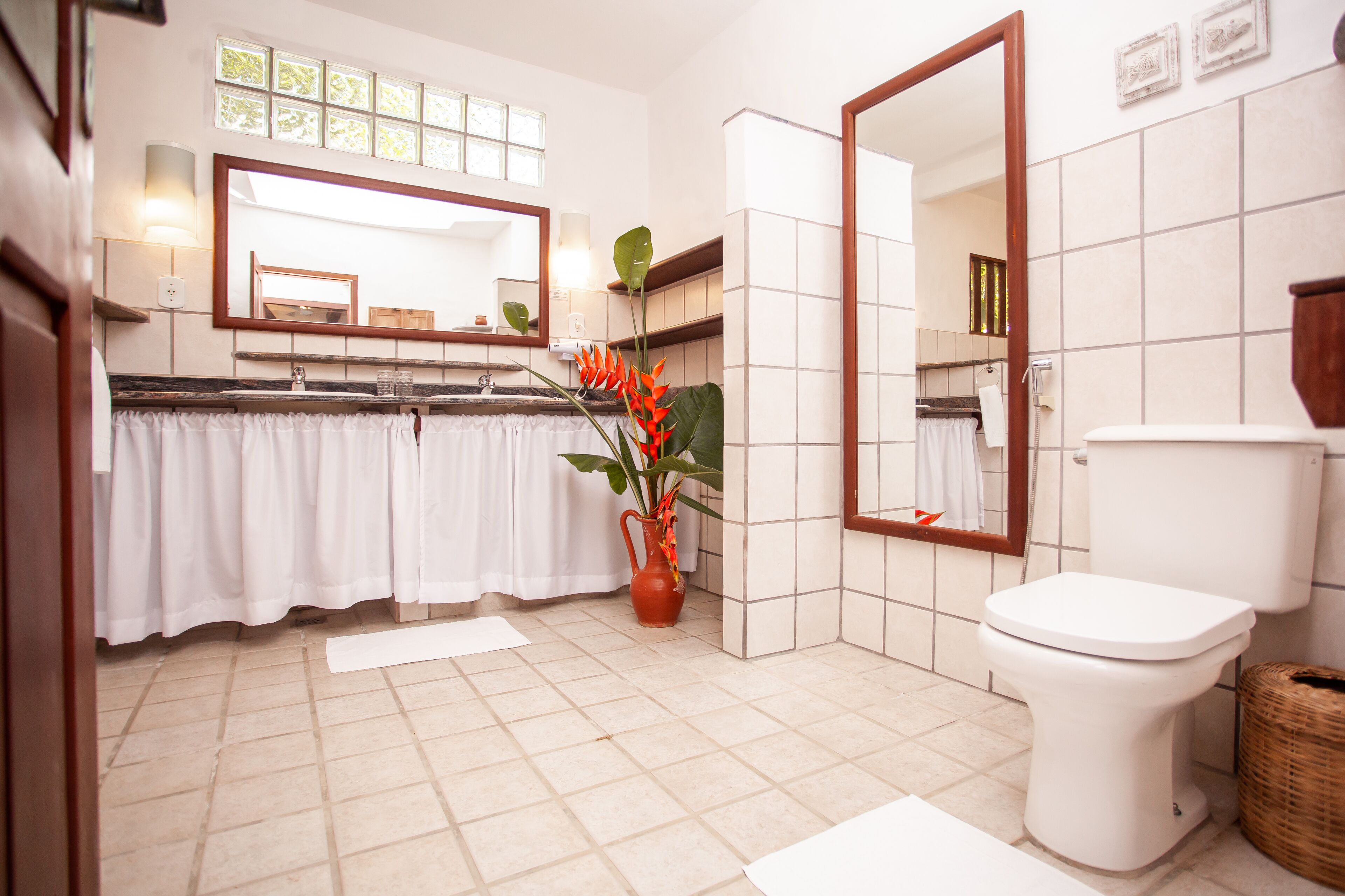 A bathroom with a toilet, a sink, a mirror, and a potted plant.