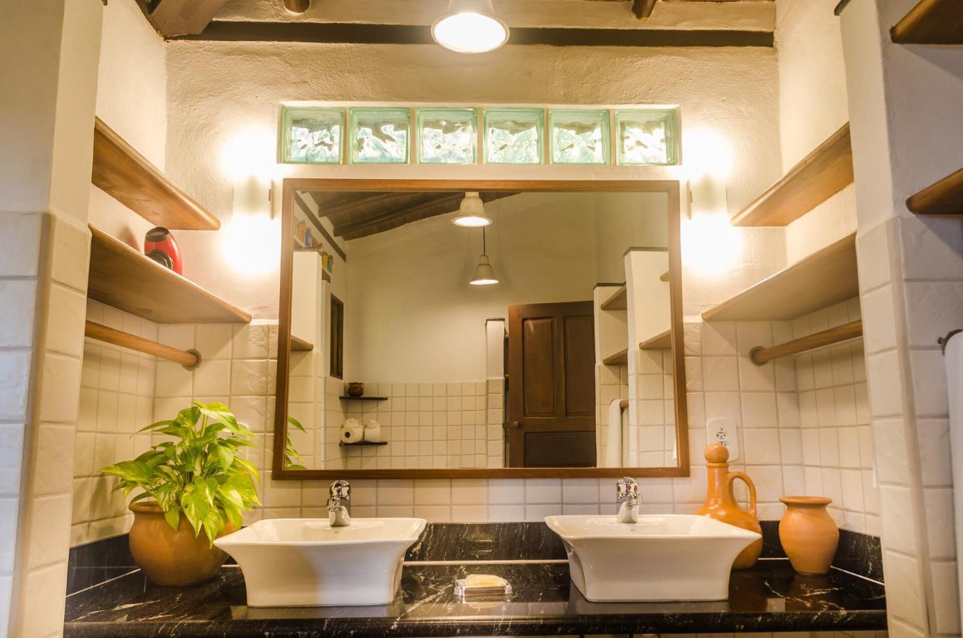 A bathroom with two sinks, a large mirror, and a potted plant.