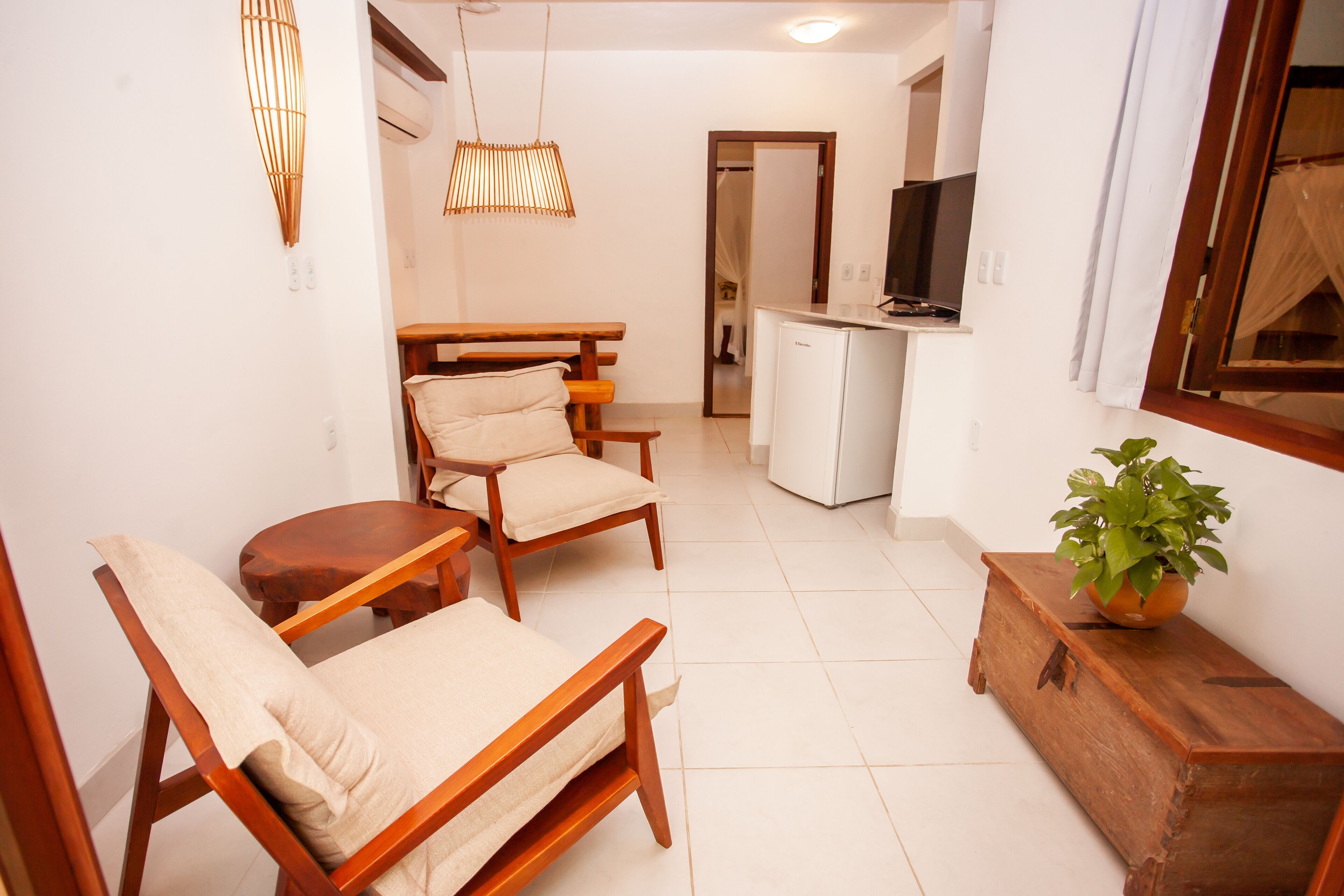 A compact living space with a dining area, a kitchenette, and a seating area with a wooden bench and chairs.