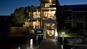 Un edificio moderno de varios pisos con un muelle y barcos.