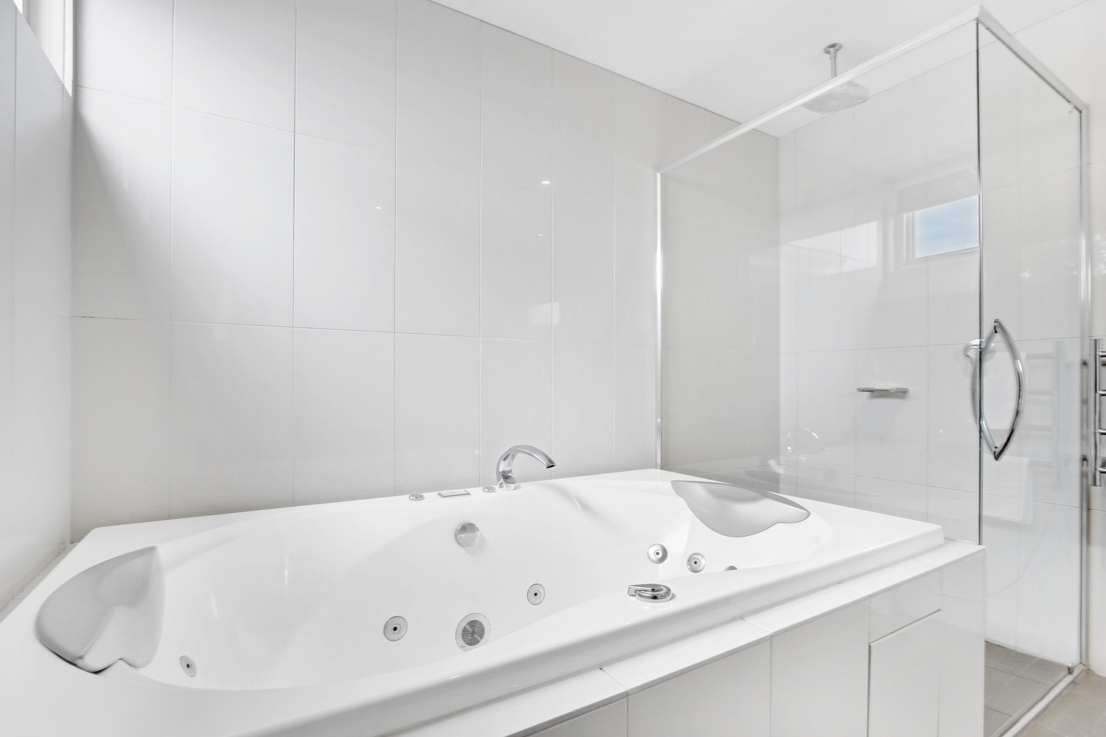 A modern bathroom with a large white bathtub, a glass shower enclosure, and a sleek vanity.