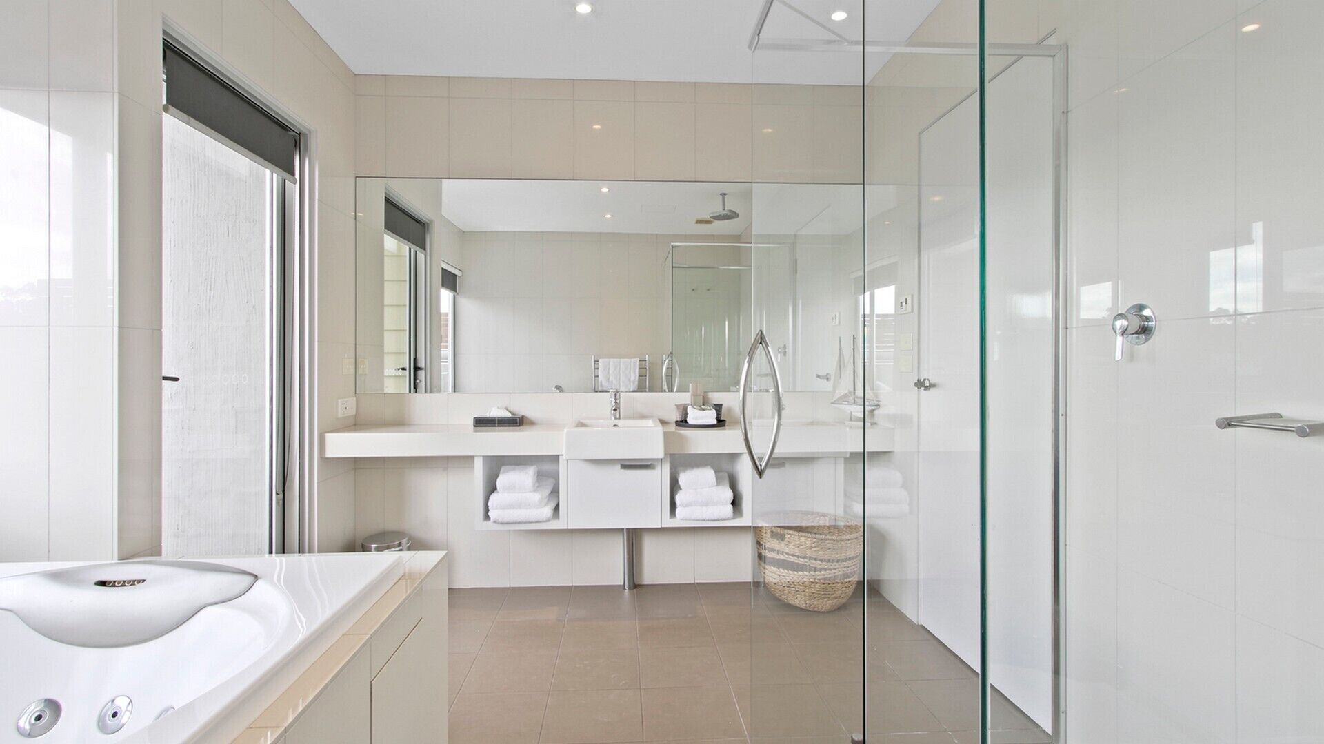Un baño moderno con cabina de ducha de vidrio, una bañera independiente y un lavamanos con espejo.