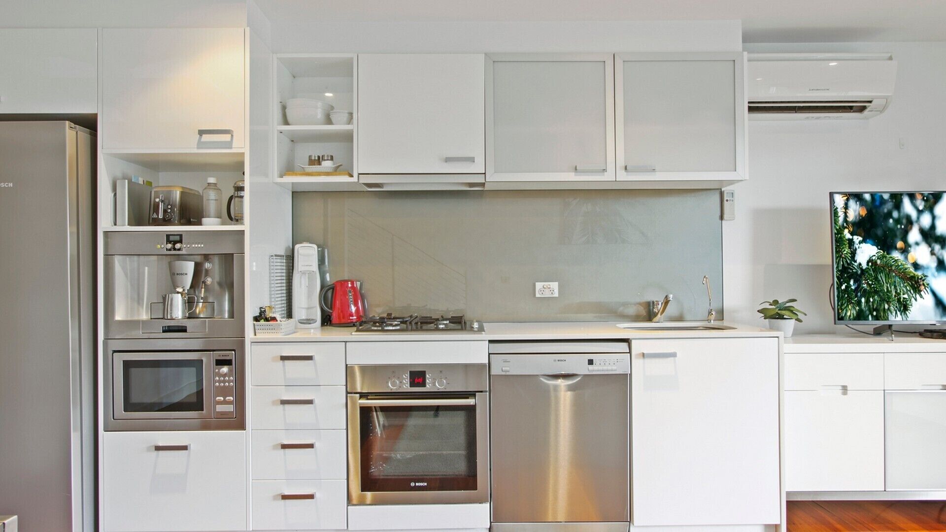 Una cocina moderna con armarios blancos, electrodomésticos de acero inoxidable y lavavajillas integrado.