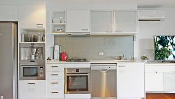 Una cocina moderna con armarios blancos, electrodomésticos de acero inoxidable y lavavajillas integrado.