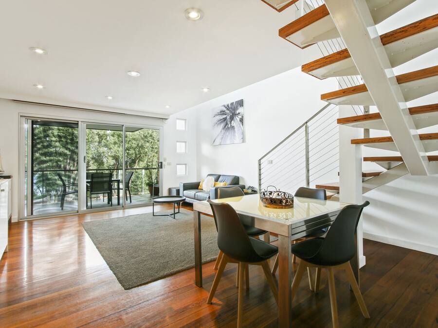 A modern interior with a dining area, a staircase, and a view of the outdoors.