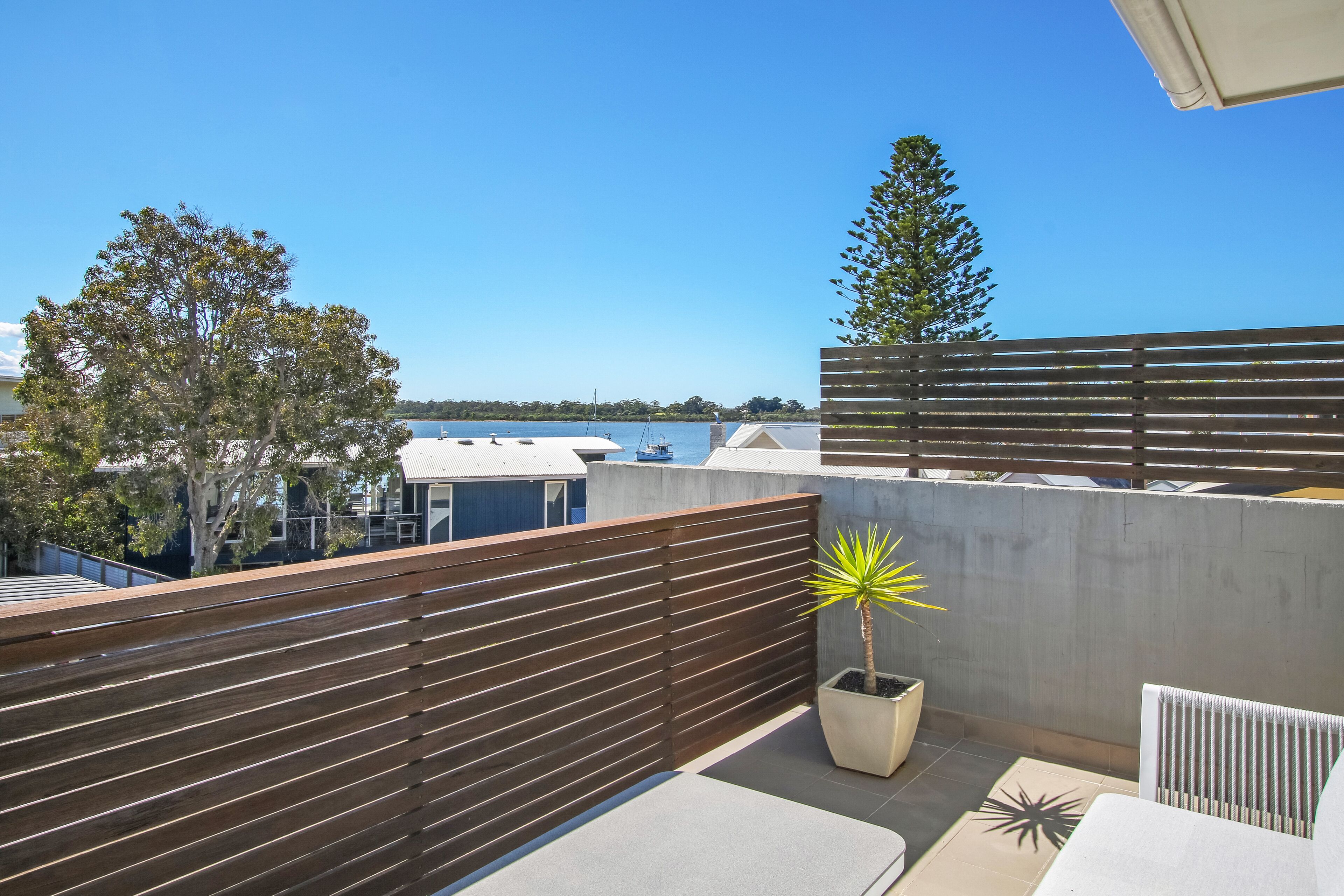 A rooftop terrace with a view of the sea, a potted plant, and a white radiator.