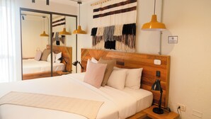 Een hotelkamer met een groot bed, een houten hoofdbord, twee nachtkastjes met lampen, een spiegel en een wanddecoratie.