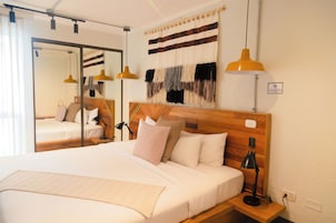 Ein Hotelzimmer mit einem großen Bett, einem Holz-Kopfteil, zwei Nachttischen mit Lampen, einem Spiegel und einer Wanddekoration.