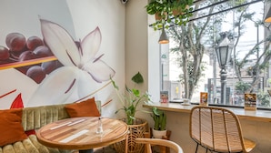 Een gezellig zithoekje met een ronde houten tafel, een comfortabele bank en een rieten fauteuil.