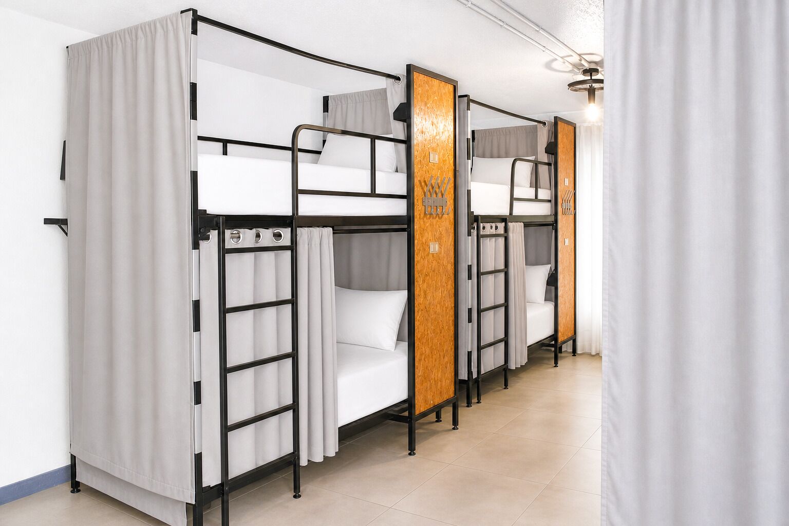 Una fila de literas con cortinas, un panel de madera y una lámpara.