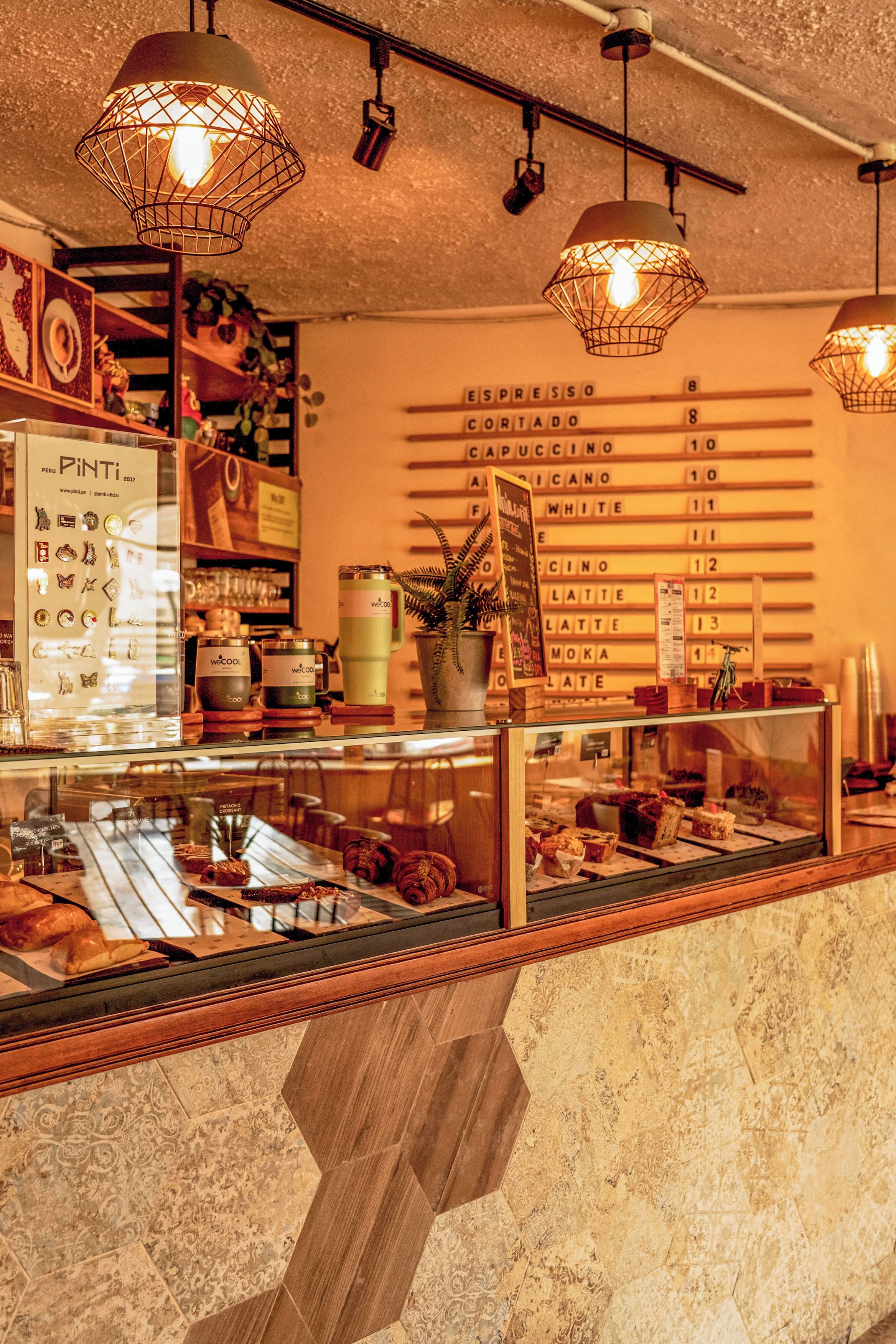 Ein Café-Interieur mit einer Speisekarte, einer Espressomaschine und einer Auswahl an Gebäck.