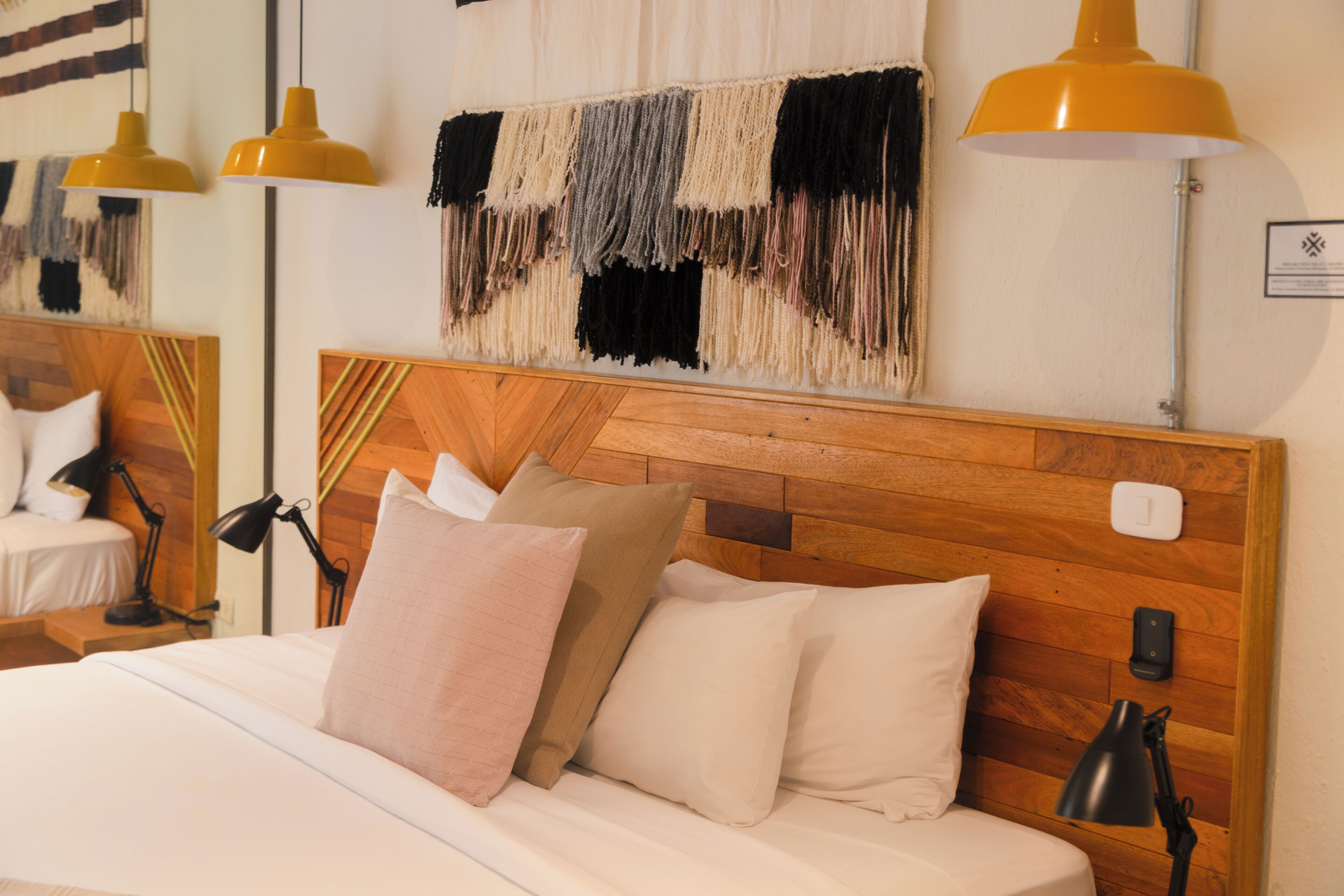 A neatly made bed with a wooden headboard, multiple pillows, and two bedside lamps.