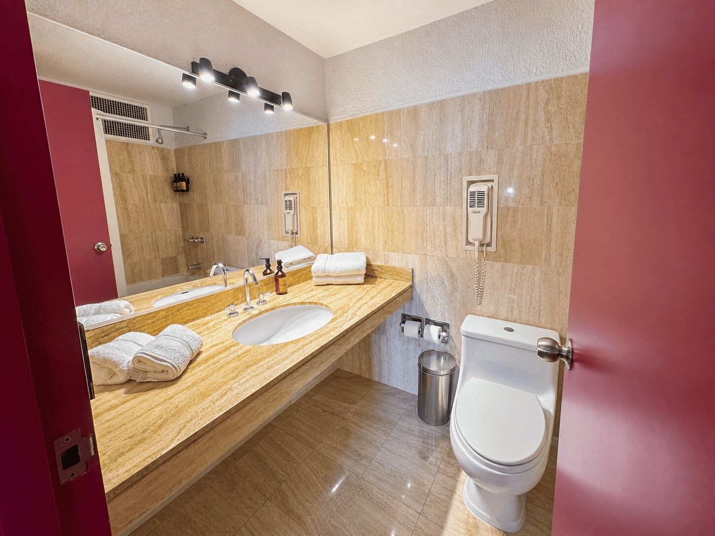 Ein modernes Badezimmer mit zwei Waschbecken, einem großen Spiegel, einer Toilette und einem Föhn an der Wand.