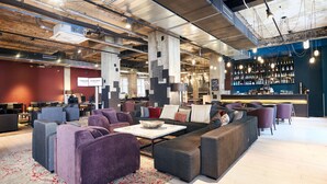 Un espace détente moderne avec des canapés, une table basse et un bar doté d’étagères remplies de bouteilles.
