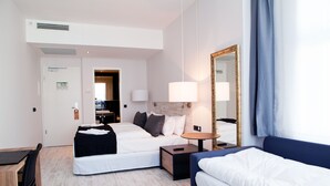 Une chambre d’hôtel avec deux lits, un bureau, une chaise, une lampe et un miroir.