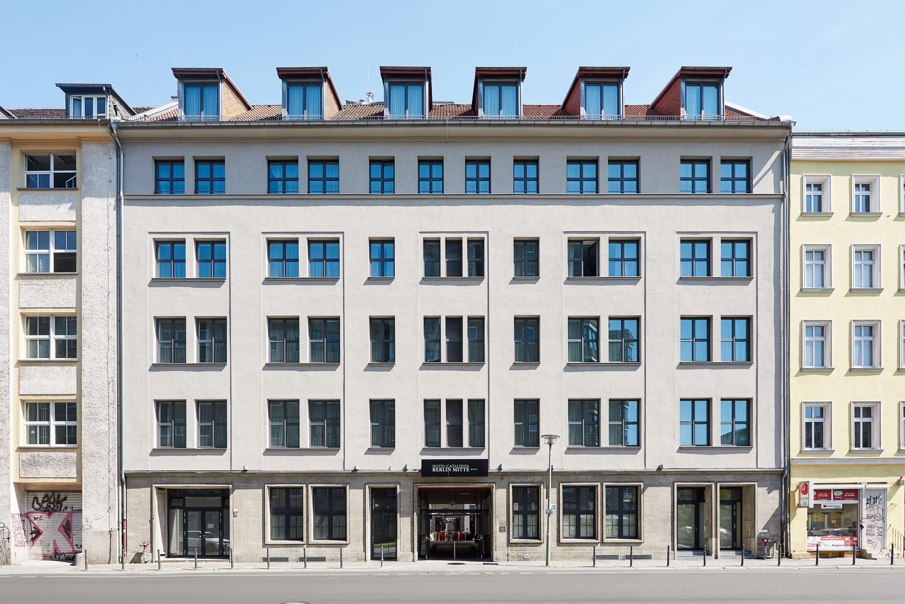 A multi-story building with a central entrance, large windows, and a flat roof.