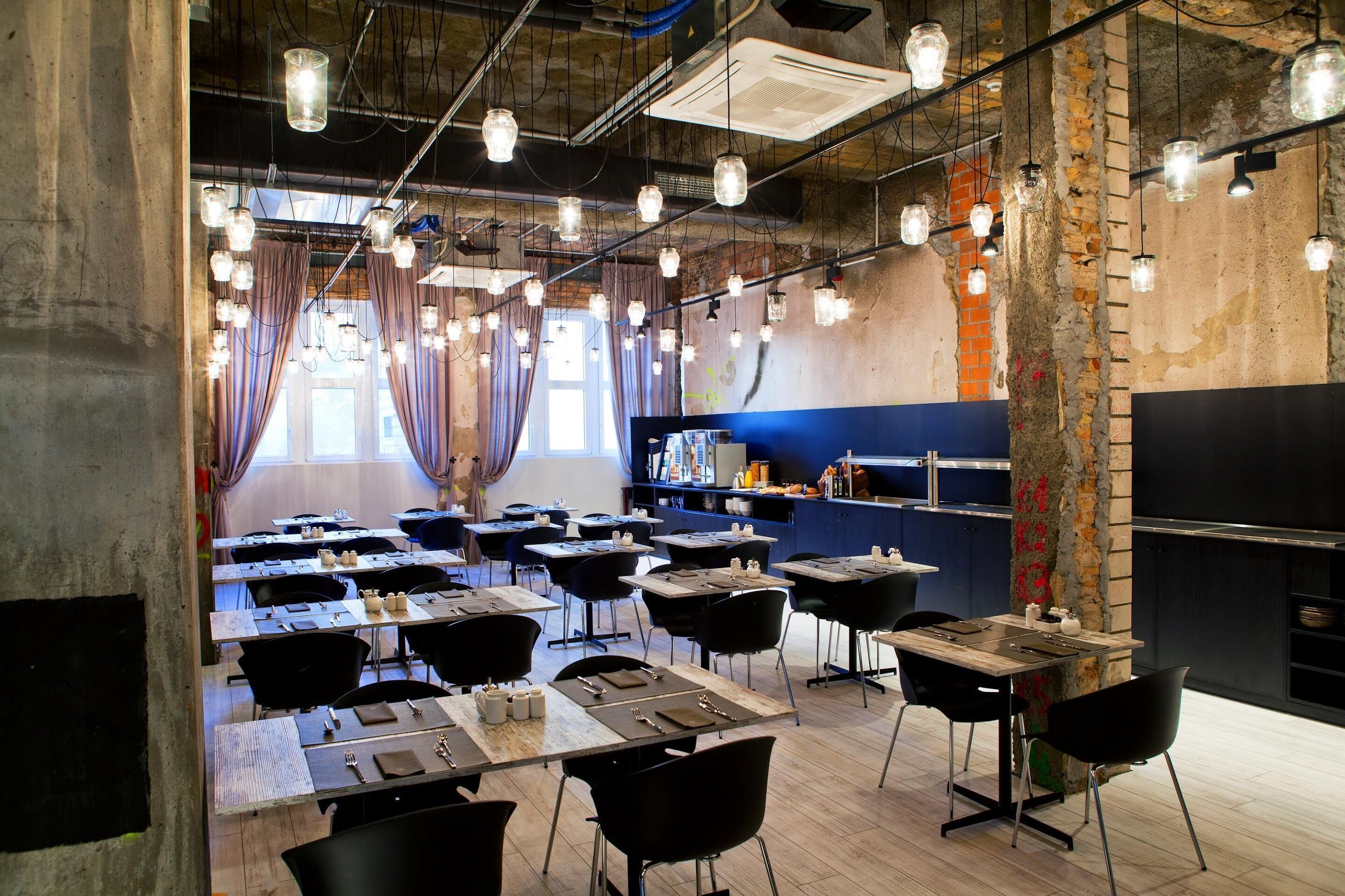 A dining area with tables set for meals, hanging light fixtures, and a brick wall.