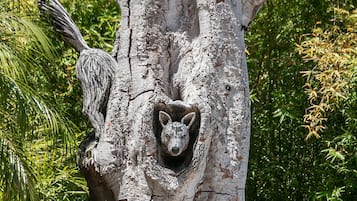 A tree with a carved bear face and a carved bird perched on it.