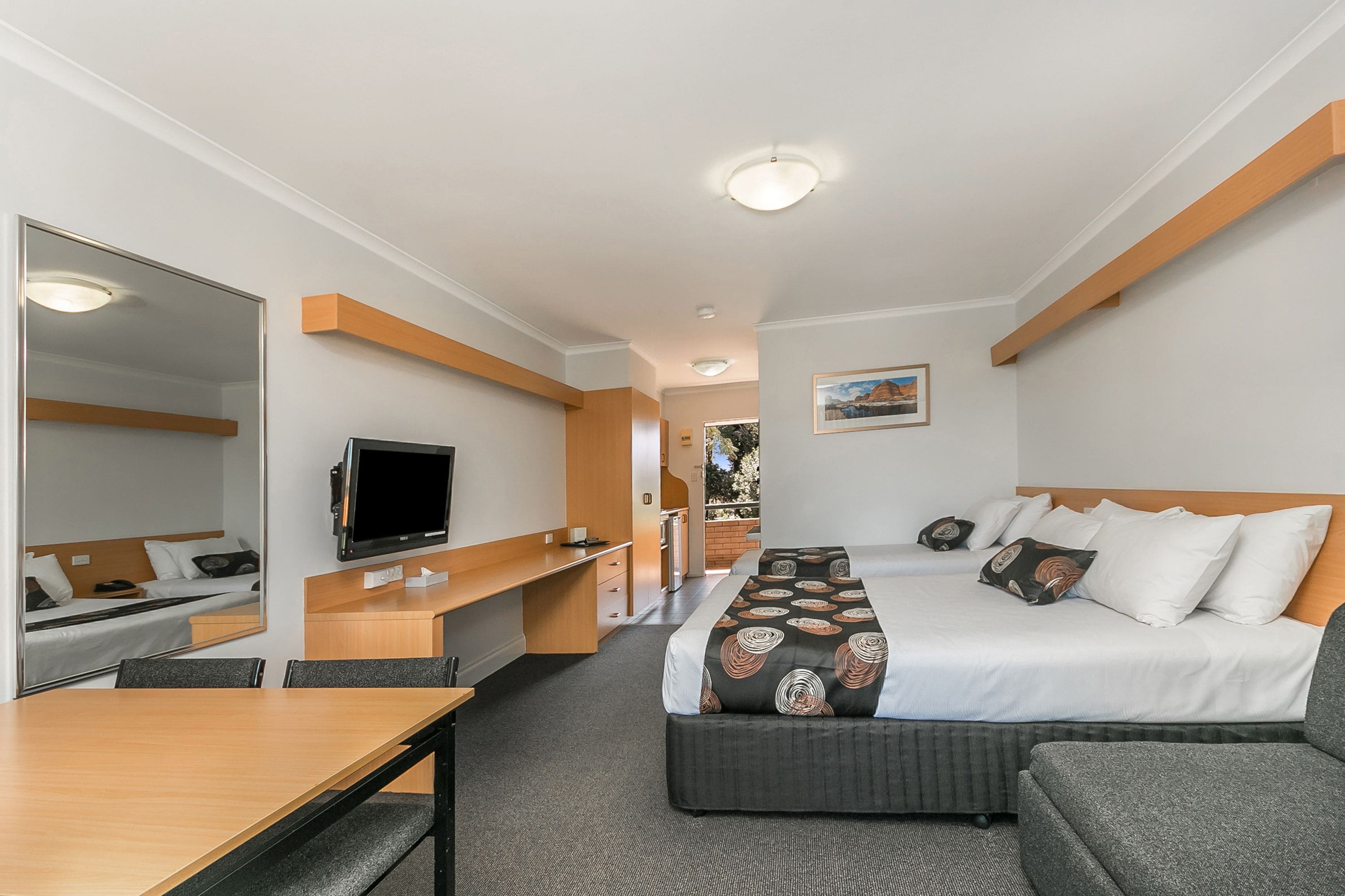 Ein Hotelzimmer mit Bett, Schreibtisch, Fernseher und Spiegel.
