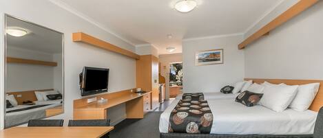 Een hotelkamer met een bed, een bureau, een televisie en een spiegel.