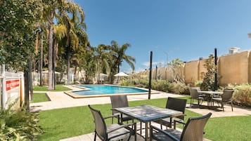 Una piscina al aire libre, sombrillas, sillones reclinables de piscina