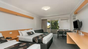 Hotellihuone, jossa on kaksi sänkyä, työpöytä, televisio ja parveke, jolta on näkymä.