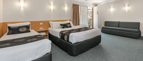 Une chambre d’hôtel avec deux lits, un canapé et une fenêtre avec des rideaux.