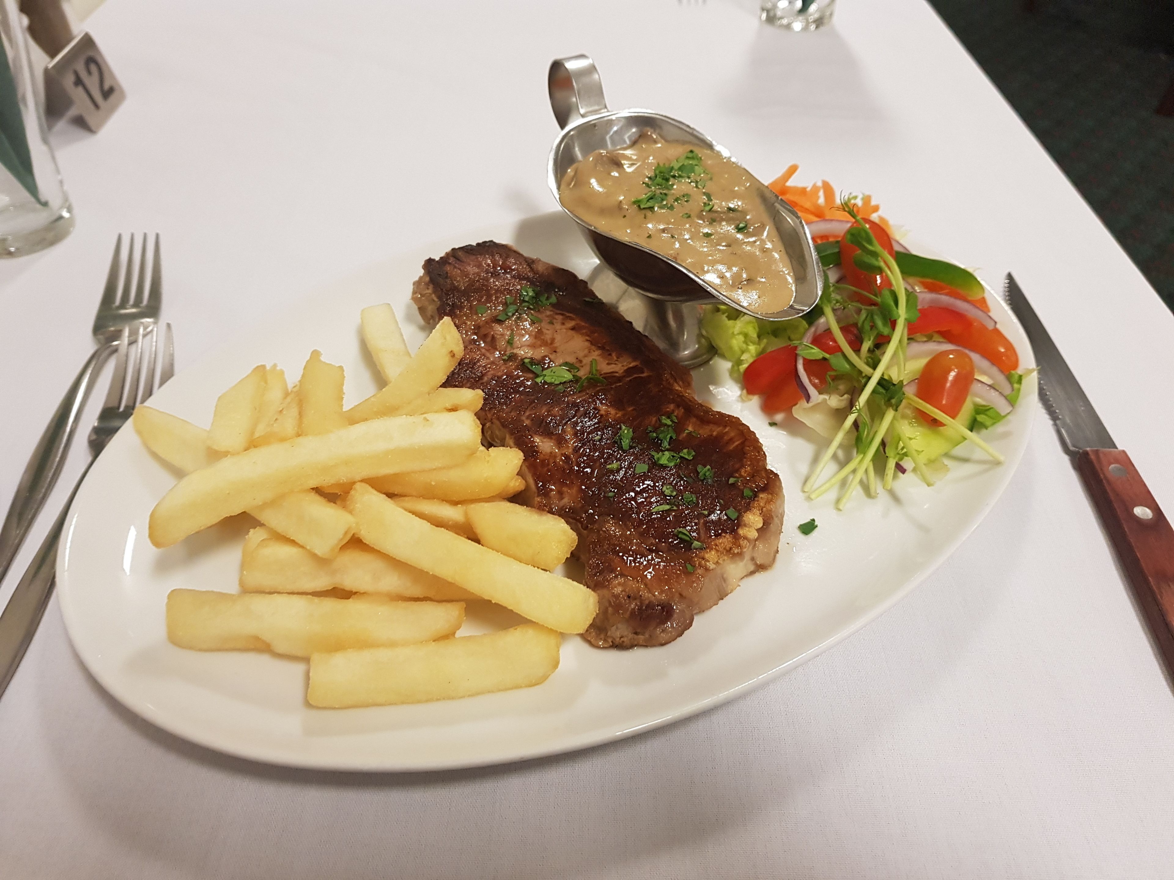 Un plato con un bistec, papas fritas y una ensalada.