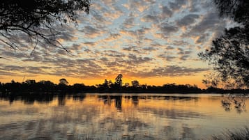 A calm lake at sunset with trees silhouetted against the sky.