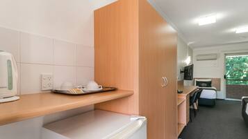 A compact kitchenette with a coffee maker, a small refrigerator, and a breakfast tray on the counter.