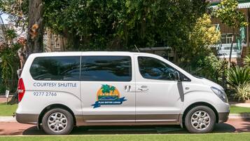 A white shuttle with "COURTESY SHUTTLE" and "FLAG MOTOR LODGE" branding, parked on a street.