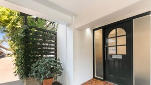Entrada de un edificio con puerta negra, un letrero que indica restaurante, suelo de baldosas y una planta en maceta.